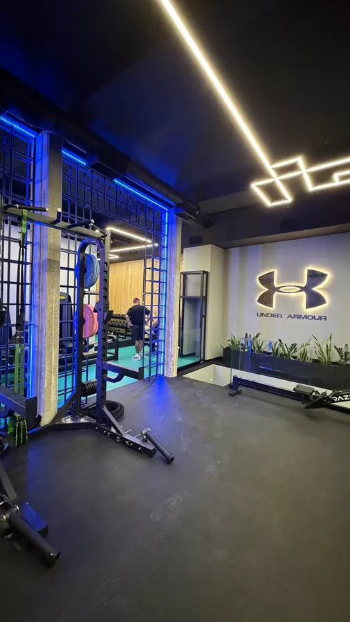 Το rack ελεύθερων βαρών μπροστά από τον τοίχο Under Armour
